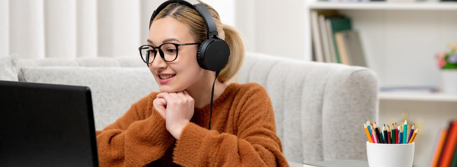 A student with headphones at a laptop during an online English course