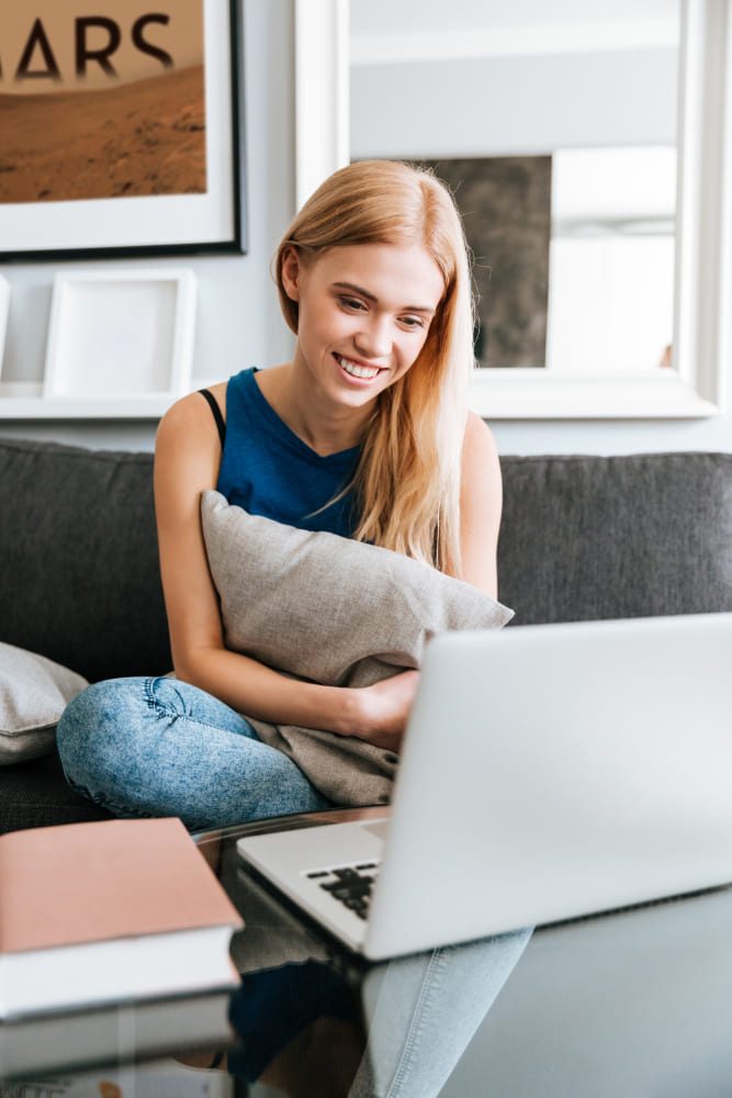 A woman with a laptop at home on the sofa during an online English lesson